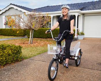 Woman smiling and riding a custom three wheel bike with basket tray
